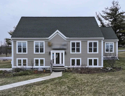 Three-story cape-style house with munton windows and taupe clapboard siding.