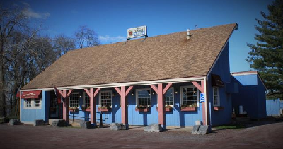 Building with offset roof, painted blue, with covered walkway and windowboxes.